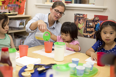 View of a child care classroom arranged neatly with shelves and tables.