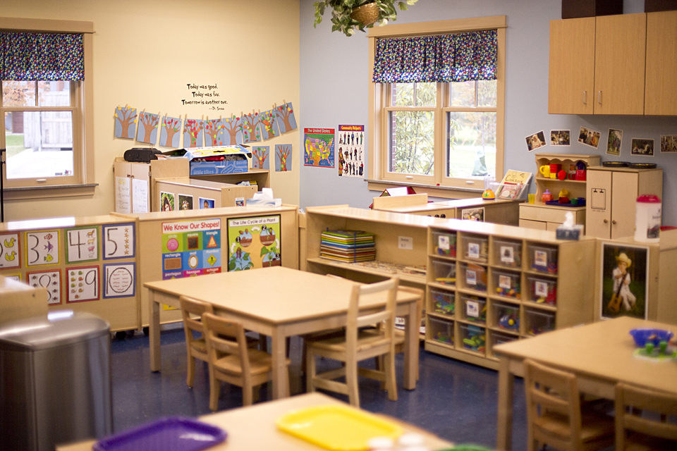 View of a child care classroom arranged neatly with shelves and tables.