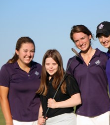 Four members of a golf team are outside, smiling at the camera.