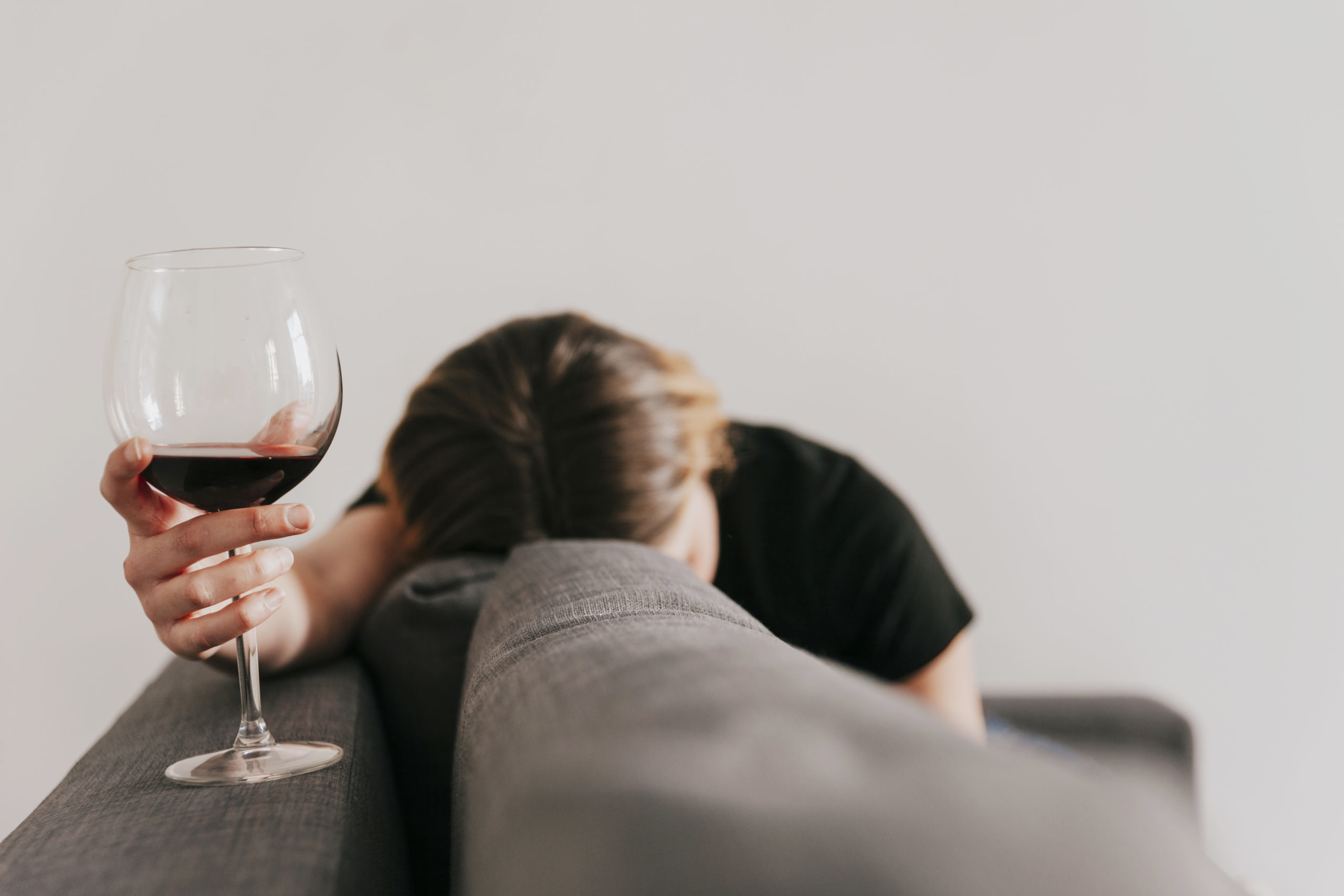 Sad woman with wine on a couch