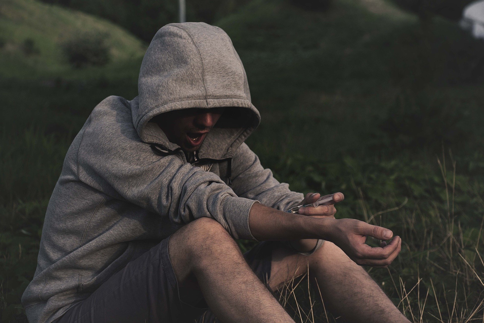 An addict wearing a hoodie using illegal drugs