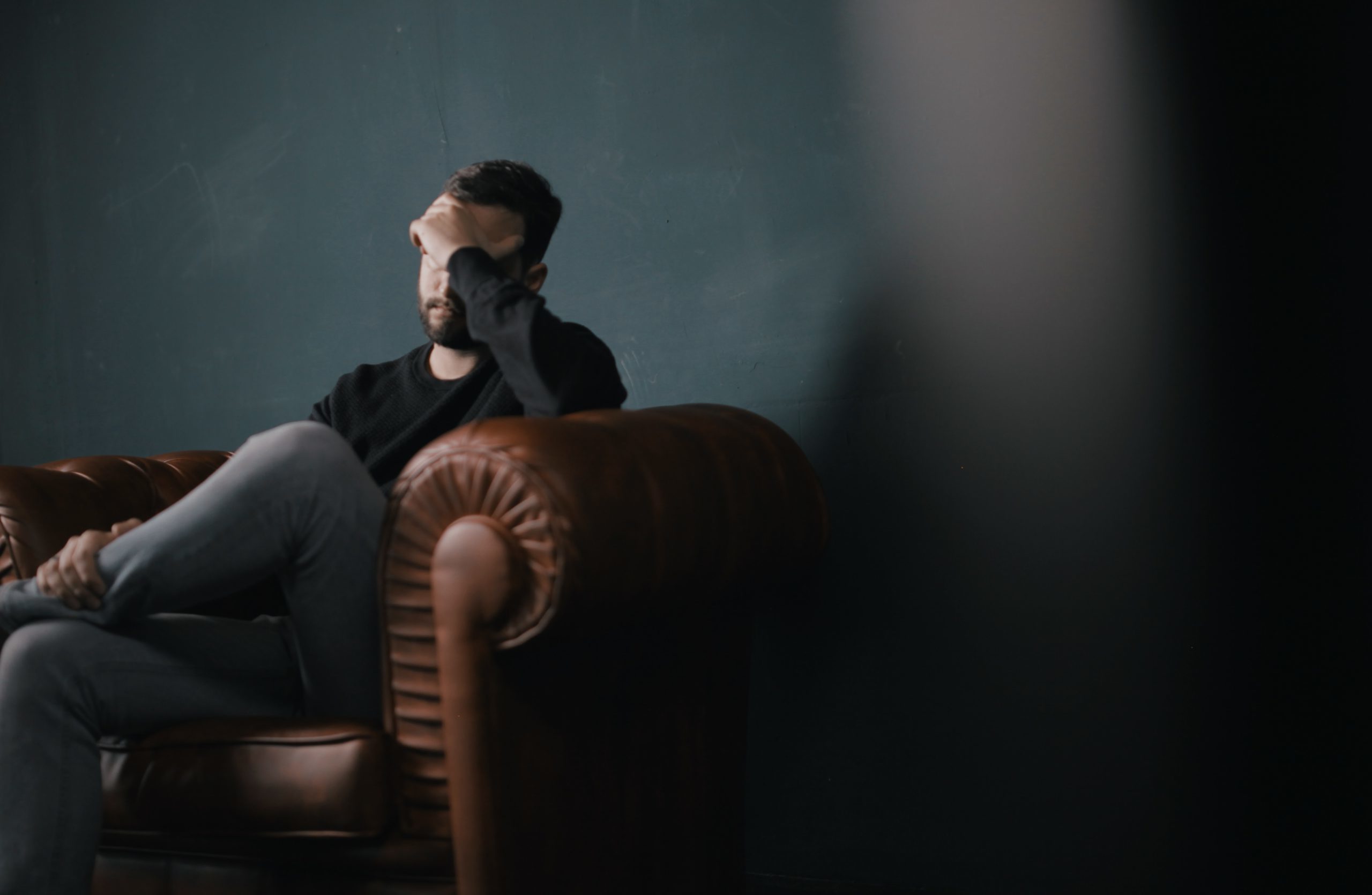 Man sitting on couch against a wall