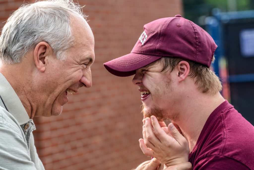 Father and son with Down syndrome laughing together.