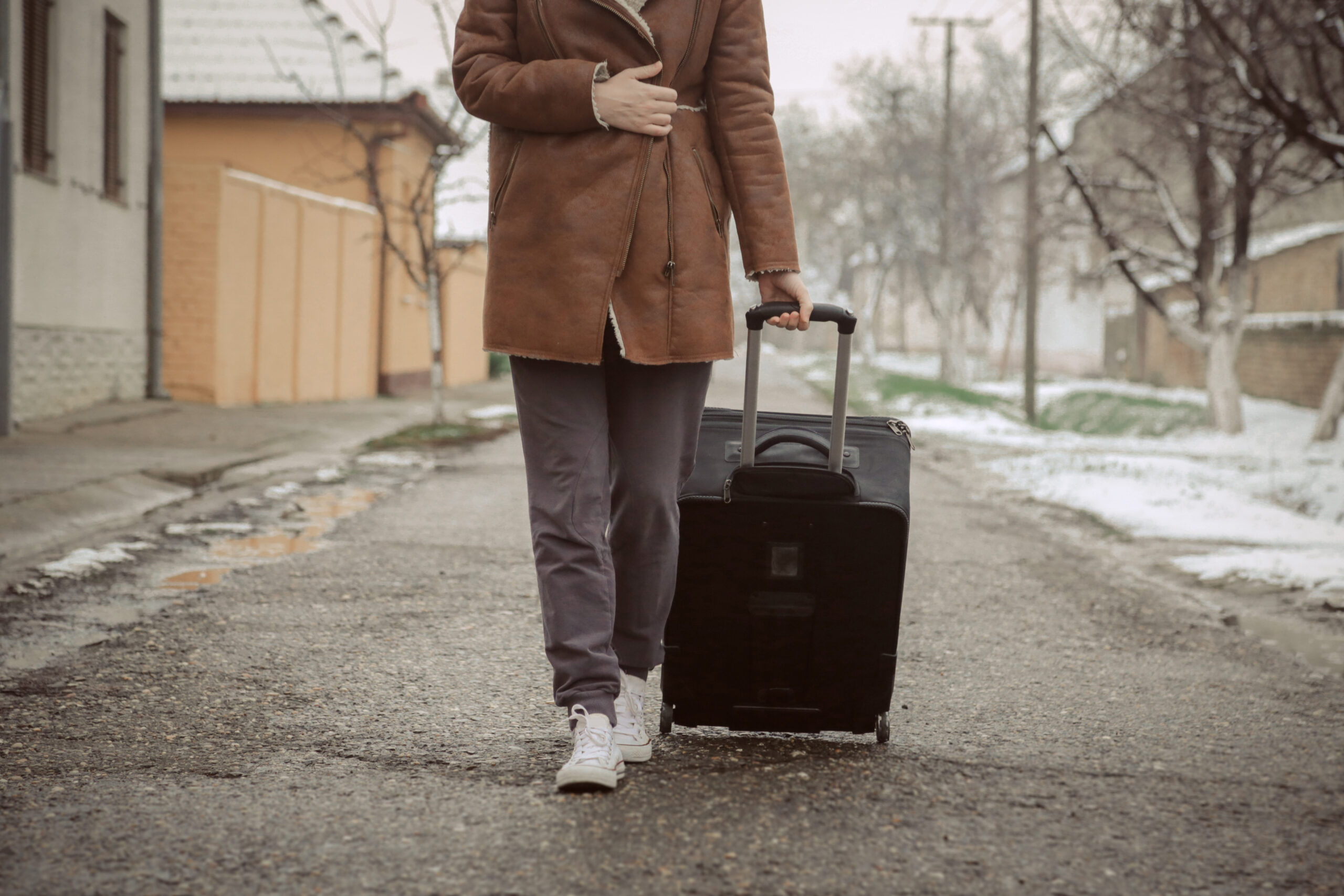 Person walking down a street rolling a suitcase