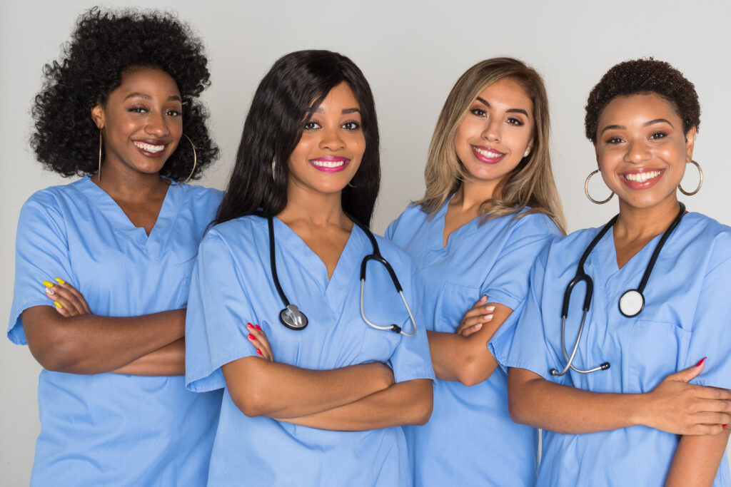 Group of four women nurses wearing blue scrubs standing together