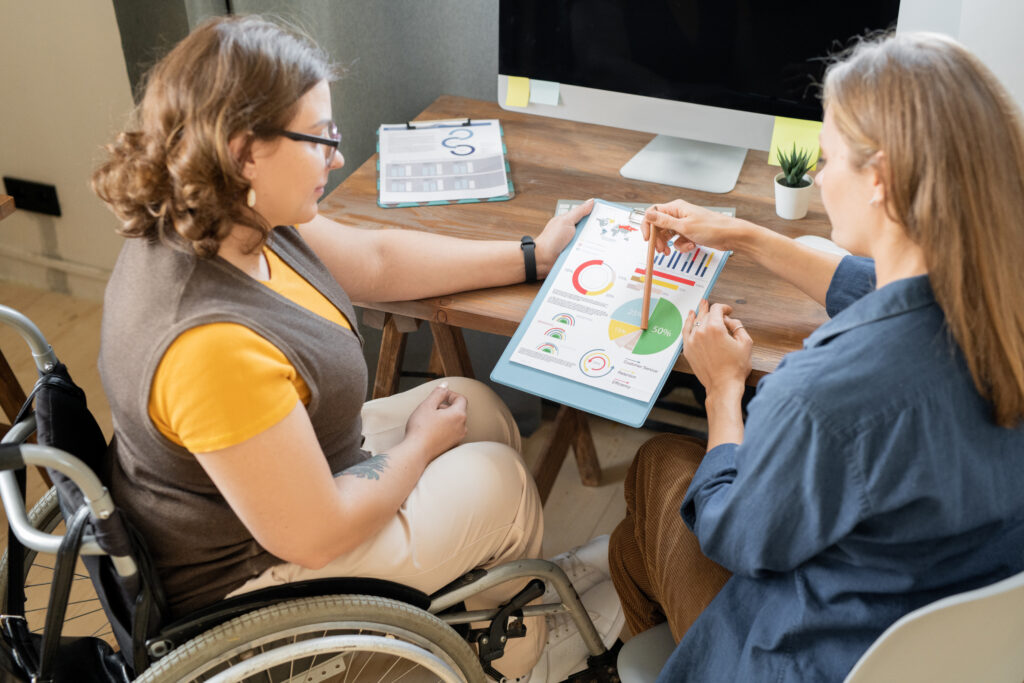 Two women sitting at a table discussing a chart. 