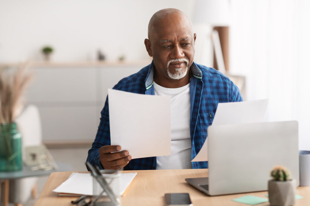 Older african american male sitting at a table examining papers