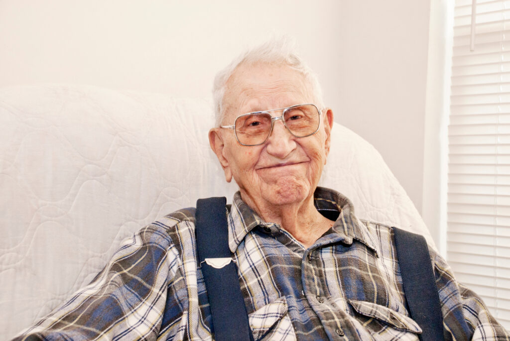 Older man sitting on a couch and smiling. 