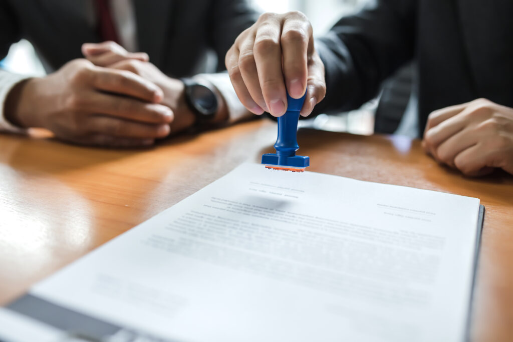 Business person stamping with approved stamp on document at meeting.