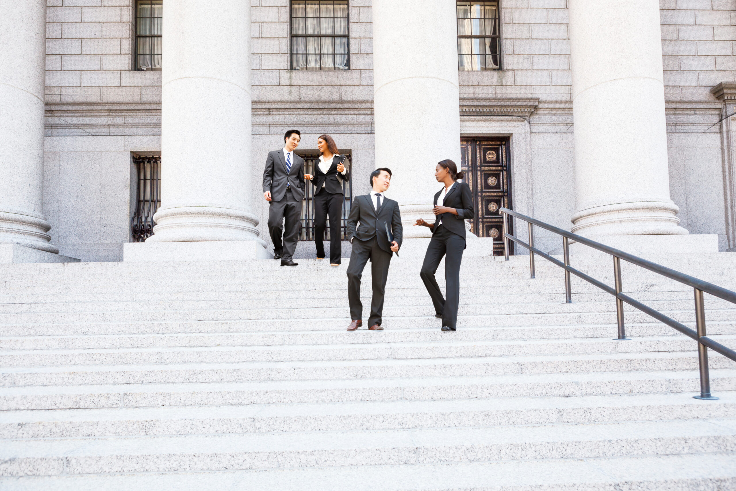 Two people in business suits standing on the steps of a government building having a conversation