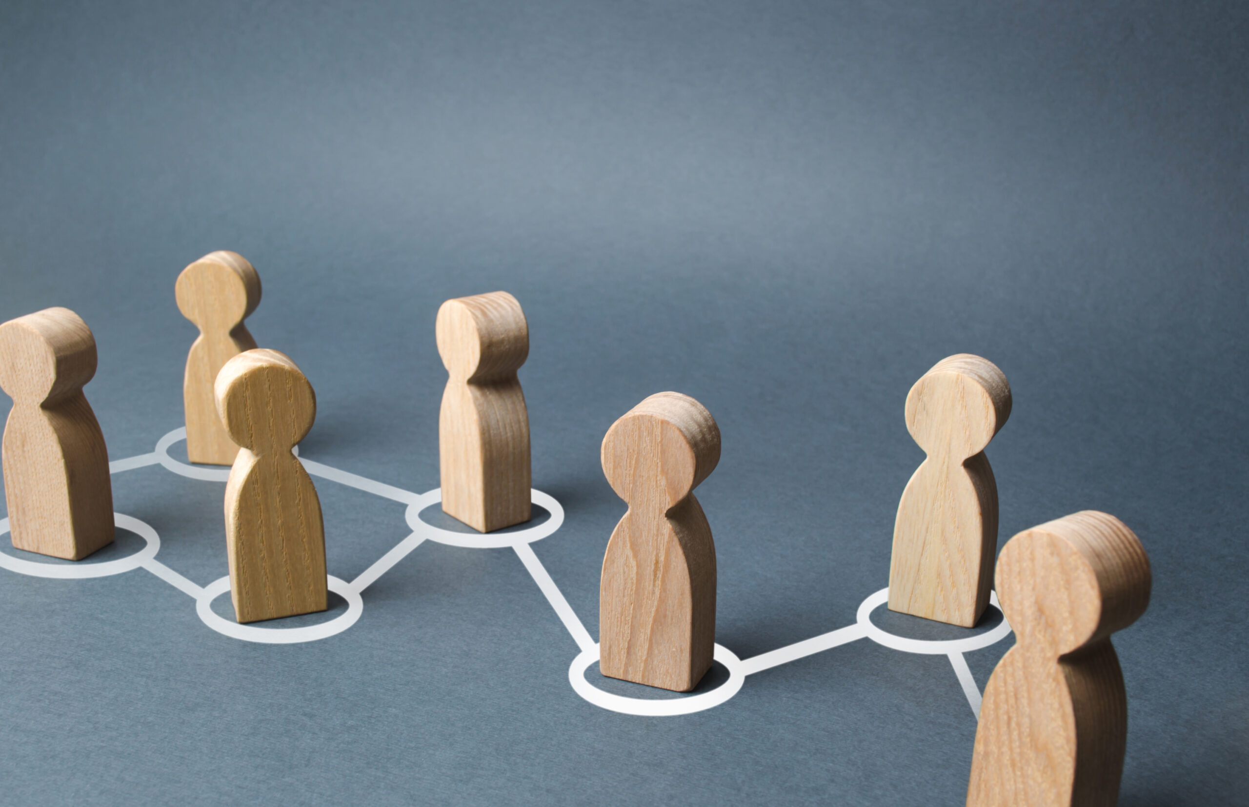 Wooden people inside circles on a table that are all connected with lines.