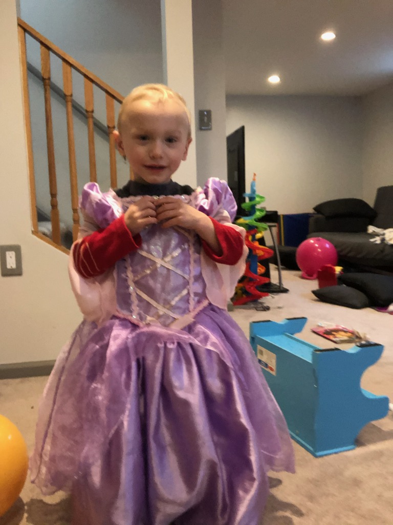 Boy wearing a purple princess dress up dress.