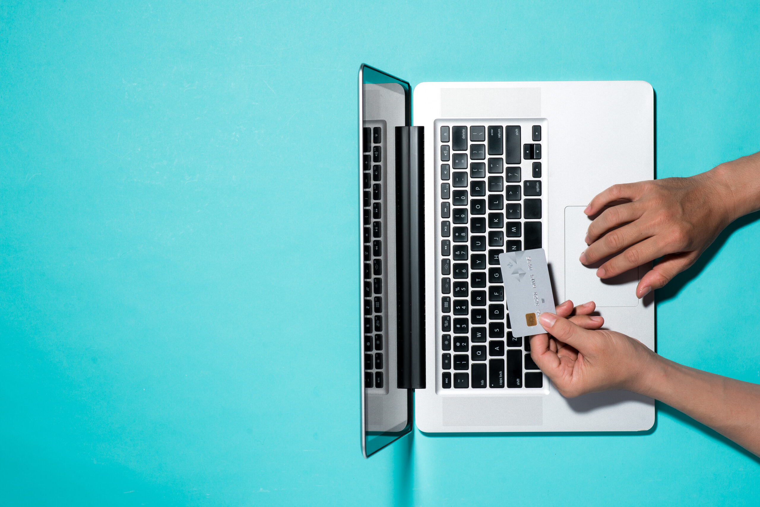 Hands Holding Credit Card at Laptop