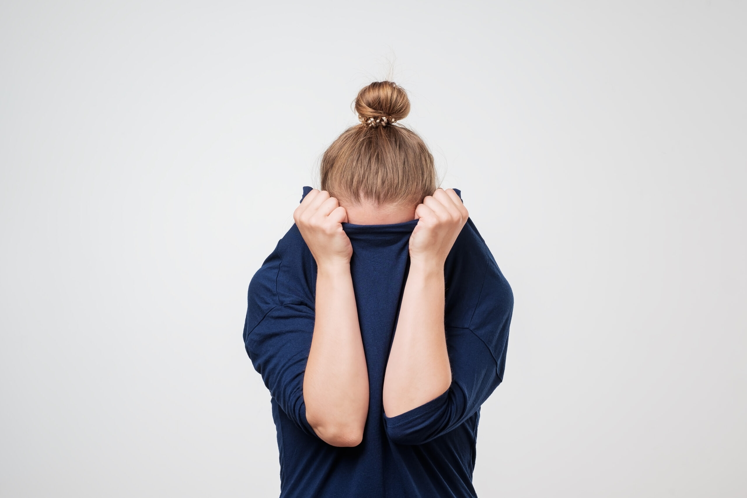 Person hiding their face inside their shirt