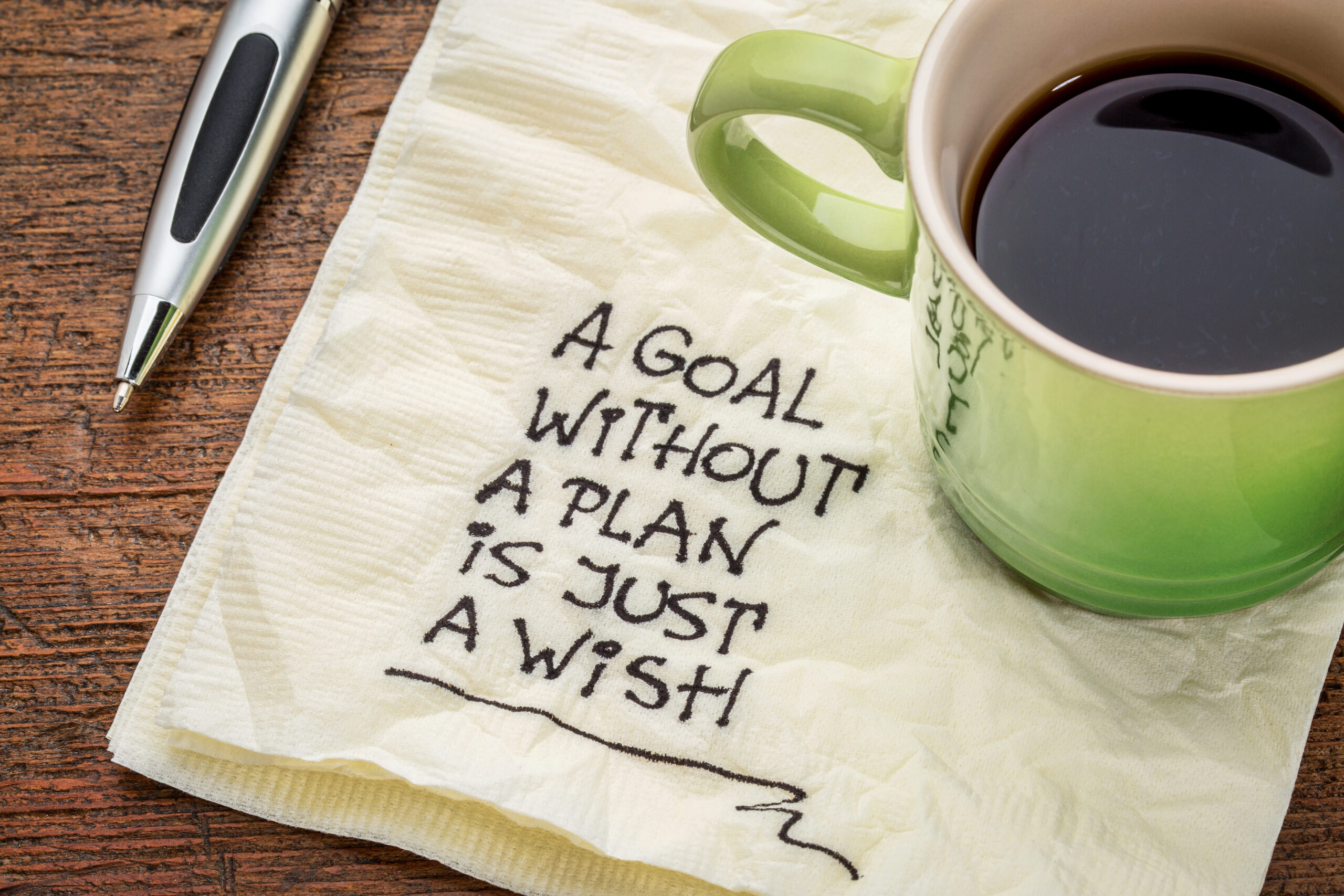 Coffeecup with napkin that has written on it "a goal without a plan is just a wish"