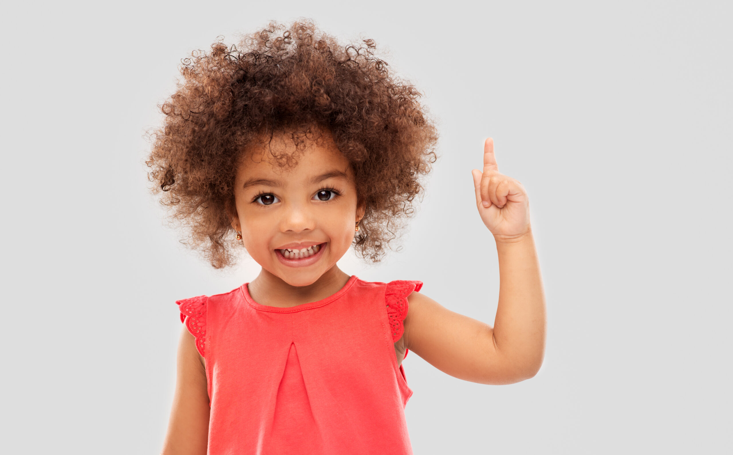 Child smiling pointing finger up.