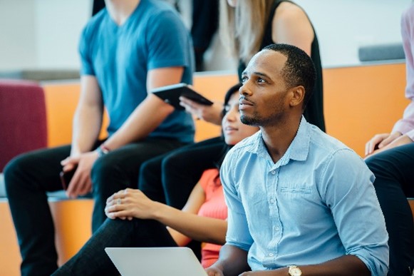 Man holding a laptop in a class.